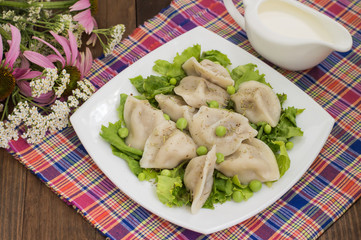Dumplings with minced chicken on a plate  fresh herbs and peas. Wooden background. Close-up