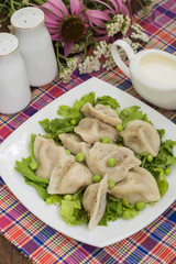 Dumplings with minced chicken on a plate  fresh herbs and peas. Wooden background. Close-up