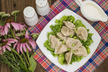 Dumplings with minced chicken on a plate  fresh herbs and peas. Wooden background. Close-up