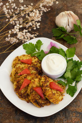 Zucchini Pancakes with sour cream, tomatoes and herbs. Old background. Top view. Close-up