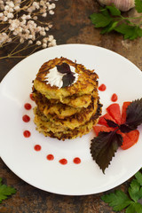 Zucchini Pancakes with sour cream, tomatoes and herbs. Old background. Close-up