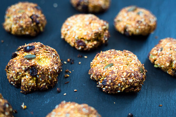 Homemade Oatmeal Cookies with Sesame Seeds, Nuts, Dried Fruits and Honey on Dark Background, Horizontal View