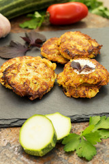Zucchini Pancakes with sour cream, tomatoes and herbs. Old background. Close-up