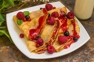 Pancakes with raspberries, currants, sugar and mint. Old background. Close-up