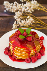 Pancakes with raspberry jam and fresh berries. Wooden background. Close-up