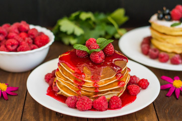 Pancakes with raspberry jam and fresh berries. Wooden background. Close-up