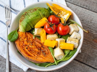 Salad with grilled vegetables: grilled sweet potatoes, tomatoes, avocados, spinach, tofu, pepper in a white bowl.  Love for a healthy raw food concept.