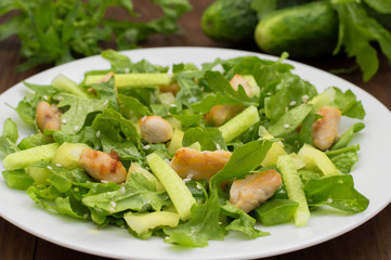 Arugula salad, paprika, cucumber, fried chicken and sesame seeds. Wooden background. Close-up