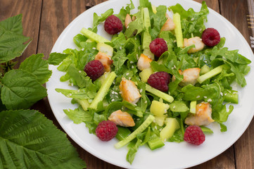 Salad with raspberries, arugula, cucumber, paprika, roasted chicken and sesame. Wooden background. Close-up