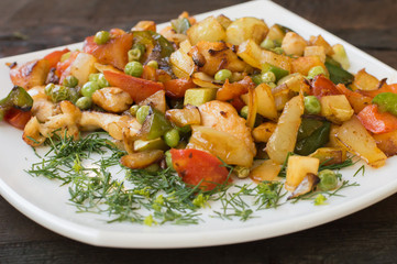 Saute vegetables and roasted chicken. Wooden table. Rural background. Close-up