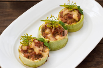 Courgettes stuffed with tomatoes, minced meat, cheese and spices. Wooden background. Top view. Close-up