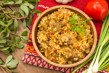 Uzbek pilaf - a dish consisting of rice and meat. At the traditional wooden background. Top view. Close-up