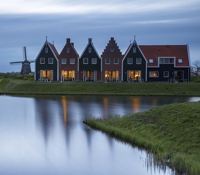 Traditional row houses and windmill by canal at dusk, Netherlands