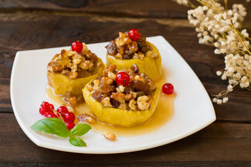 Baked apples with raisins, walnuts and honey for dessert. Wooden rustic background. Close-up