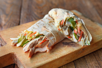 Burrito with pork meat and vegetables at wood desk