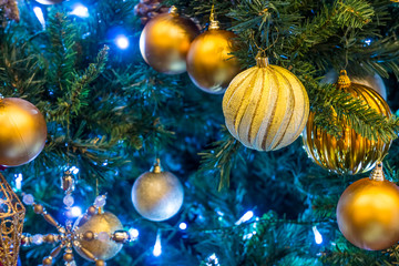 Obraz na płótnie Canvas Golden Christmas baubles on branch. Lights and spherical decoration are used to festoon a tree.