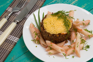Meat casserole, Italian pasta and cheese crisps. Wooden background. Close-up