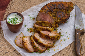 Pork steak cooked on the grill, marinated in herbs and rosemary, served  a table with tzatziki sauce. Background paper for baking. Top view. Close-up