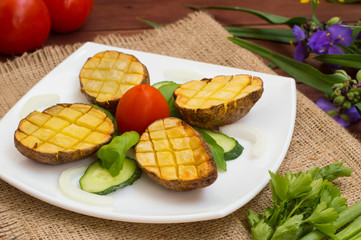 Baked potatoes with vegetables on the background color. Wooden table. Close-up