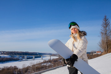 Young woman and her white snowboard on snow-covered mountainside