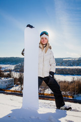 Young woman and her white snowboard on snow-covered mountainside