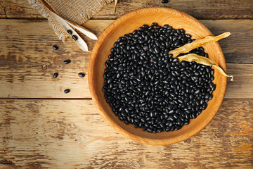 Bowl with black haricot beans on wooden table