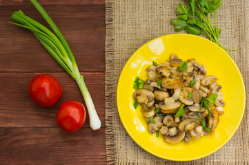 Fried mushrooms on a yellow plate. Wooden background. Top view. Close-up