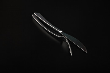 Fototapeta na wymiar Matching steel fork and knife arranged on a reflective black surface