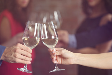Female and male hands toasting with glasses of white wine, closeup