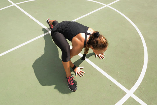 Young woman exercising on basketball court floor