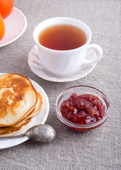 Pancakes with vintage silver spoon, cup of tea and strawberry ja