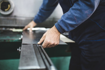 Metallurgy industry. Factory for production of heavy pellet stoves and boilers. Manual worker preparing parts for production. 