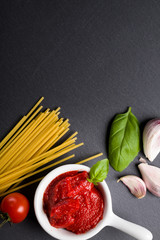 Naklejka na ściany i meble Black plate background with Italian food ingredients for cooking spaghetti with copy space.