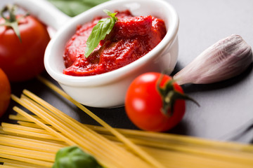 Black plate background with Italian food ingredients for cooking spaghetti.