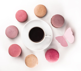 Macarons, coffee, and paper butterfly on white