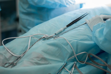 Close-up image of surgical instruments during cosmetic plastic surgery on breasts. Forceps, tweezers, doctor operating a patient. Breast augmentation, enlargement, enhancement. Hands of surgical team.