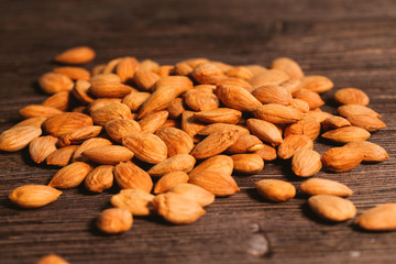 Apricot kernels are scattered on the wooden background