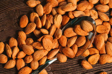 apricot kernels sprinkled with metal spoon on a wooden background