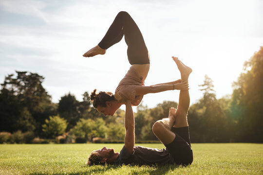 Fit young couple doing acroyoga on grass