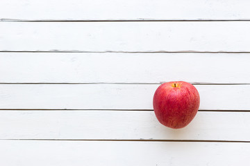 A red apple on wooden white background