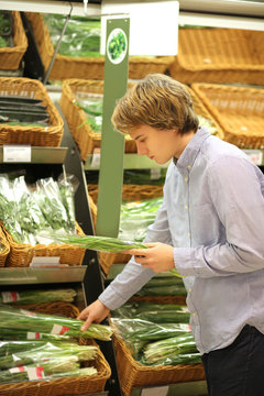 Young man in the supermarket .Young man buying vegetables at the market