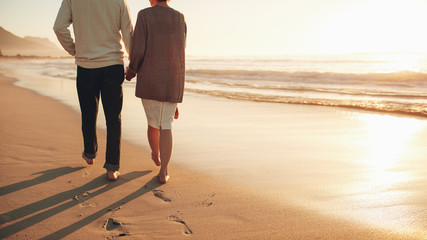 Senior couple holding hands walking on the beach
