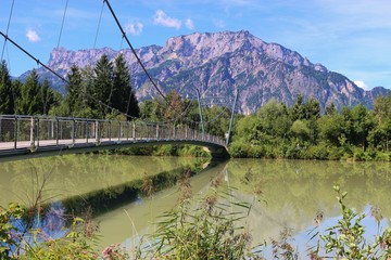 Pedestrian bridge over the Salzach river in Puch, not far from Salzburg city. In the background the mountain Untersberg. Puch, Austria, Europe. © utamaria