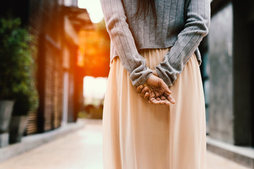 Woman hands behind her back  ,looking at something in the city.