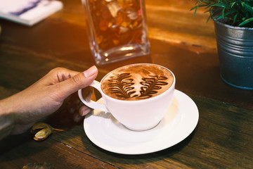 Hand holding a cup of hot cocoa on the table.
