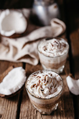 Coconut latte on a wooden table. Broken coconut. Low key food photo.