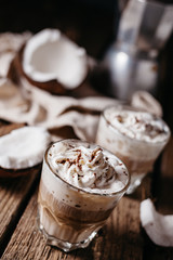 Coconut latte on a wooden table. Broken coconut. Low key food photo.
