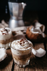Coconut latte on a wooden table. Broken coconut. Low key food photo.