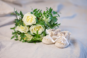 Little baby's bootees and flowers on a linen openwork plaid. Wai