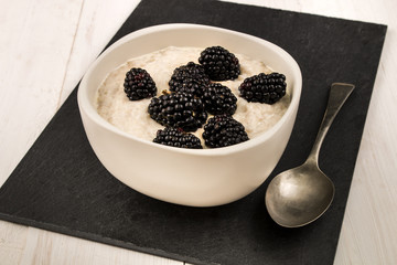 creamy porridge with blackberries in a bowl